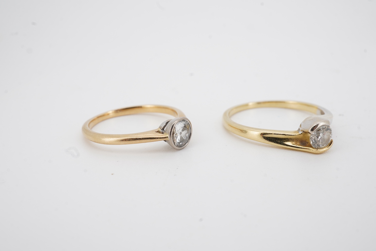 A modern two colour 18ct gold and solitaire diamond set ring, size N/O, the stone weight 0.33ct, together with a yellow metal and collet set solitaire diamond ring, size K, the stone weighing approximately 0.45ct, gross